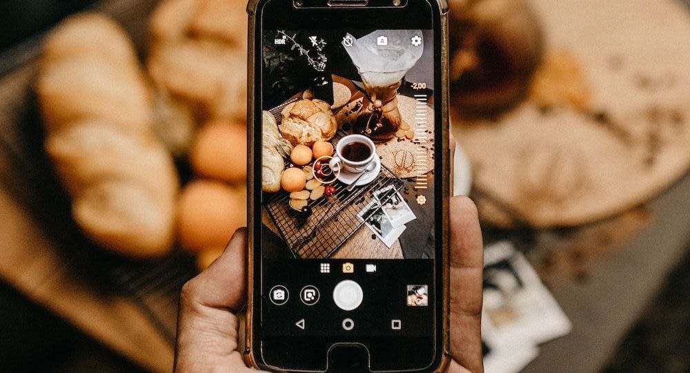 Cell phone taking a picture of coffee and pastries